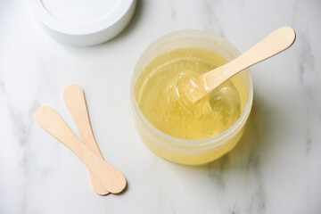Liquid yellow sugar paste or wax for epilation on wooden stick or spatula closeup