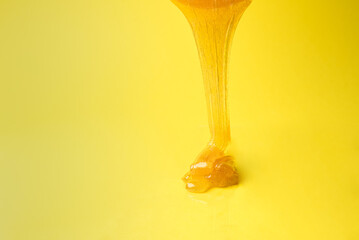 Liquid sugar wax flowing down on yellow background