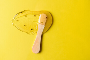 Liquid sugar wax glitter smear with spatula on yellow background