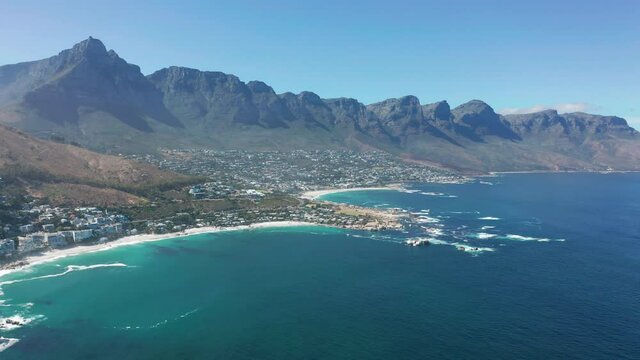 Aerial moving along the shoreline of Camps Bay, Cape Town, South Africa, with Twelve Apostles mountains. CAPE TOWN, SOUTH AFRICA.