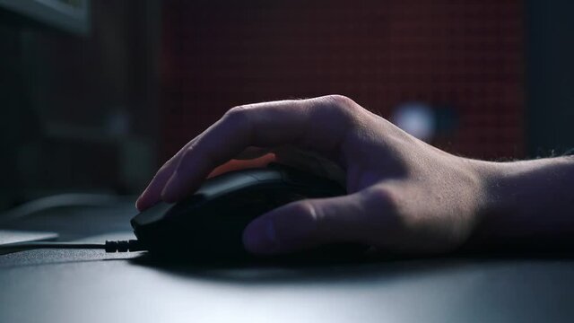 Close-up on a gamer hand playing computer games on mouses. The player actively presses his fingers on the keys, playing a shooter or MMO.