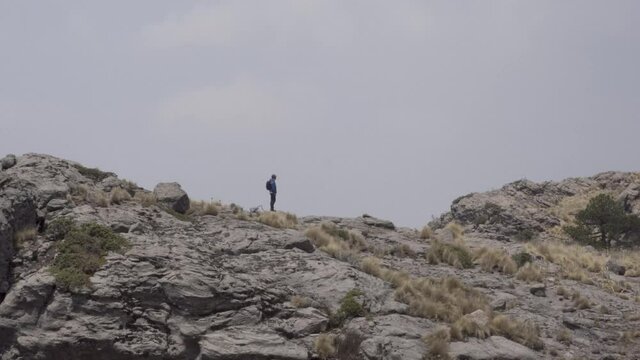 Hispanic hiker on top of mount Tlaloc under a cloudy sky in Mexico