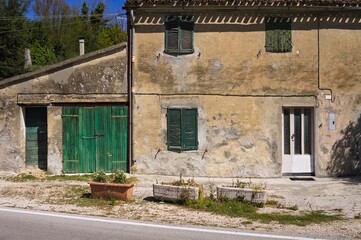 An abandoned cottage in the Italian countryside with green doors and windows (Marche, Italy, Europe)