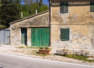 An abandoned cottage in the Italian countryside with green doors and windows (Marche, Italy, Europe)