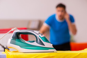 Young man husband doing ironing at home