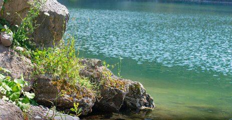 view of the lake and the green vegetation at the base of the rocky mountain - 433396503