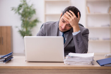 Young male employee unhappy with excessive work in the office