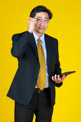 One businessman in black formal suit stand touching glasses and look at camera with tablet computer in hand. Studio shoot half body with white background.