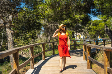 A young tourist woman walking along the wooden walkway towards Moncayo Beach in Guardamar del Segura, Alicante. Community of Valencia. Spain