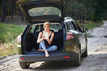 Hipster woman with long hair sitting in the back of the car enjoying freedom