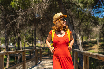 A young woman in a red dress on the path to Playa Moncayo in Guardamar del Segura, Alicante. Community of Valencia. Spain