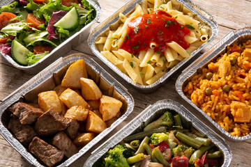 Take away healthy food in foil boxes on wooden table	