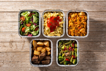 Take away healthy food in foil boxes on wooden table	