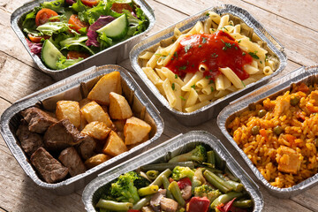 Take away healthy food in foil boxes on wooden table	