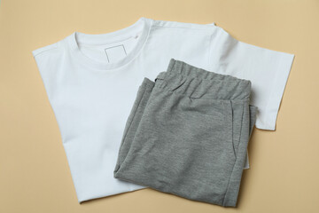 T-shirt and sweatpants on beige background, top view