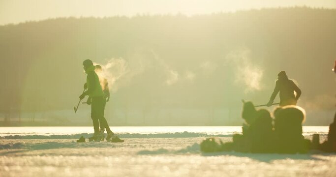 Group of teenagers playing ice hockey in golden January sunset in Oslo