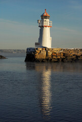 Skansen Light House, Trondheim, Norway. Standing on a mole reflected in the sea.