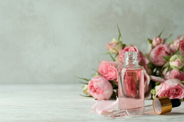 Bottle with rose essential oil on white wooden table