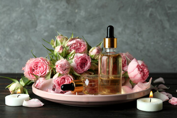 Fototapeta na wymiar Skin care concept with essential rose oil against gray textured background