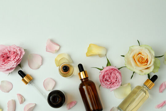 Skin care concept with essential rose oil on white background, top view