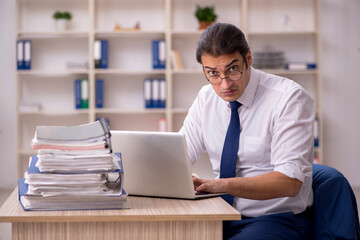 Fototapeta premium Young male employee and a lot of work in the office