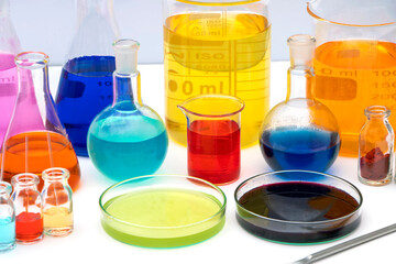 Laboratory glassware with various colored liquids in chemistry laboratory. Volumetric laboratory glassware over white background