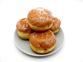 Three soufgania doughnuts without a hole in the center, sprinkled with powdered sugar.