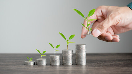 The hand of a business man is depositing money for investment There are coins that have been shown...