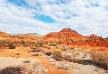 The hills are mountains of ancient sediments with patterns of erosion, red yellow and white clay and desert vegetation. View of the Altyn-Emel park in Kazakhstan