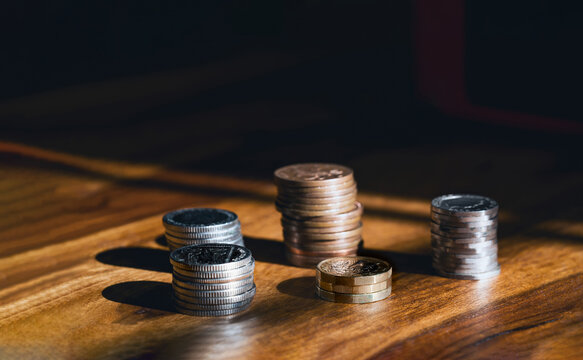 Stacks  British money sterling pound coins on wooden table, Selective focus GBP coins on the wood with shadow and light in dark room, Business and financial for money saving or investment concept