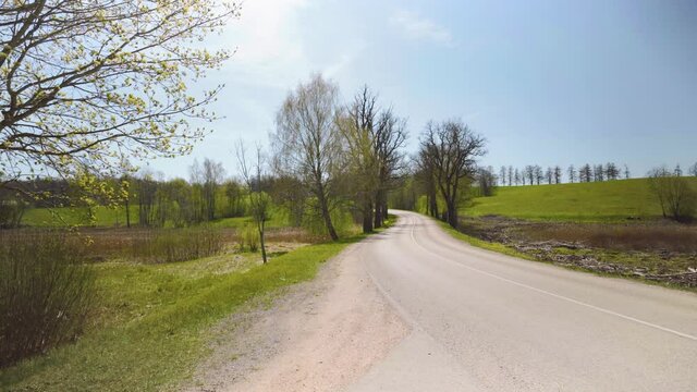 Asphalt road between agricultural fields of LatviaAsphalt road between the hills of Latvia in spring