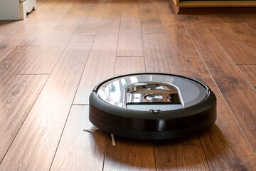 Robot vacuum cleaner on a wooden floor. The concept of a smart home.