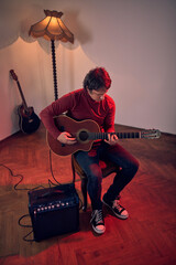 Obraz premium Male musician playing acoustic guitar on the amplifier in retro vintage room.