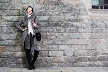 Fototapeta na wymiar cheerful female in the historical city in coat hood near wall