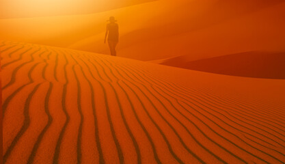Obraz premium Woman walking alone in the desert with sunset 