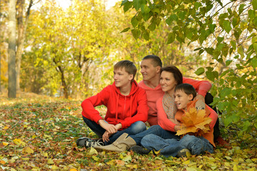Family of four relaxing  in autumn park