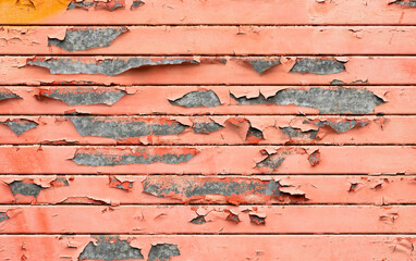 Flaking red paint on an old metal shutter.
