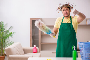 Young male contractor wearing prickly wreath on head cleaning th