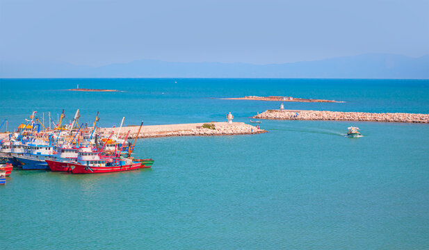 Fishing boats in Karatas Harbour at bright blue sky,  breakwater in the background - Adana, Turkey