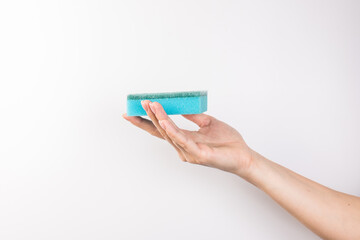 Sponge for washing dishes in female hand. Woman's hand gesture or sign isolated on white. A hand holds a sponge for washing and cleaning dishes