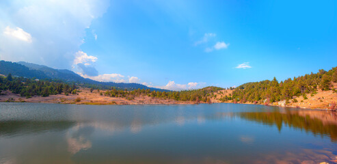 Fototapeta premium Clear reflecting lake with tree and clouds - Panoramic view on mountain lake in front of mountain range - Mersin Turkey