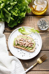 Avocado, canned tuna and boiled egg toast on wooden table background. Healthy food, avocado open sandwich for breakfast or lunch. Flat lay, top view