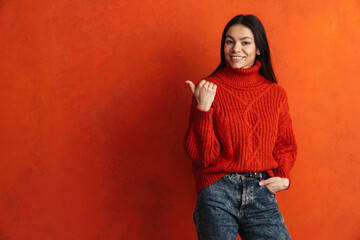 Young hispanic woman smiling and pointing finger aside