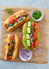 Delicious freshly cooked hot dogs with sausages, vegetables, cheese and sauce on a
