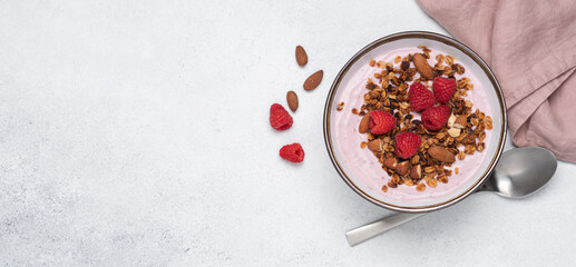 Raspberry yogurt in bowl with granola and almond nuts. Delicious healthy breakfast on white background