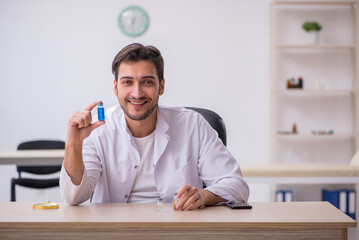 Young male chemist doctor holding vial