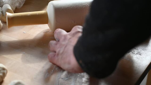 a rolling pin lies on the table a man prepares dough for chebureks makes balls of dough cuts the dough with a knife concept of homemade food. High quality 4k footage