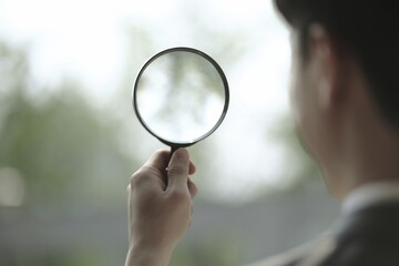 Close up of businessman holding magnifying glass