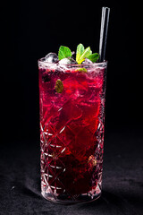 black currant lemonade with ice cubes and mint, cold summer lemonade with black currant isolated on a black background