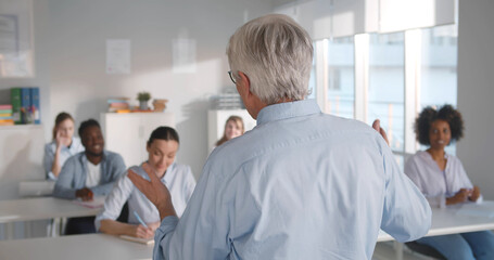 Young students listening to professor in classroom at college